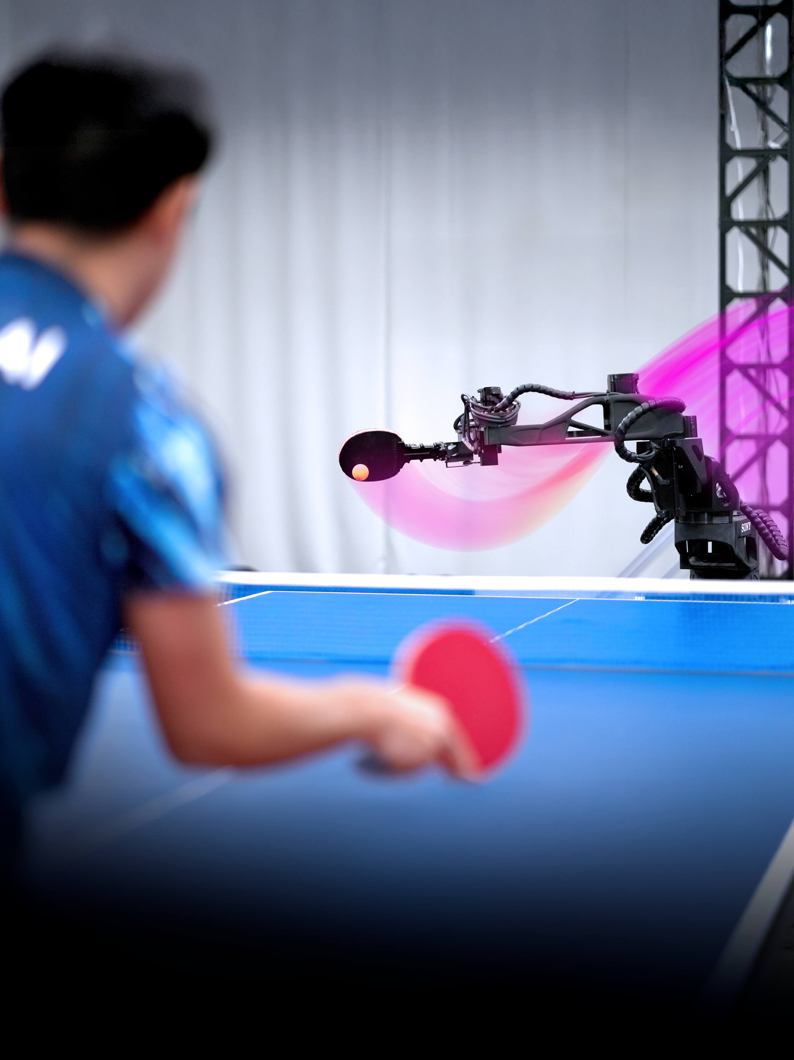 A male table tennis player plays with an autonomous robot. 