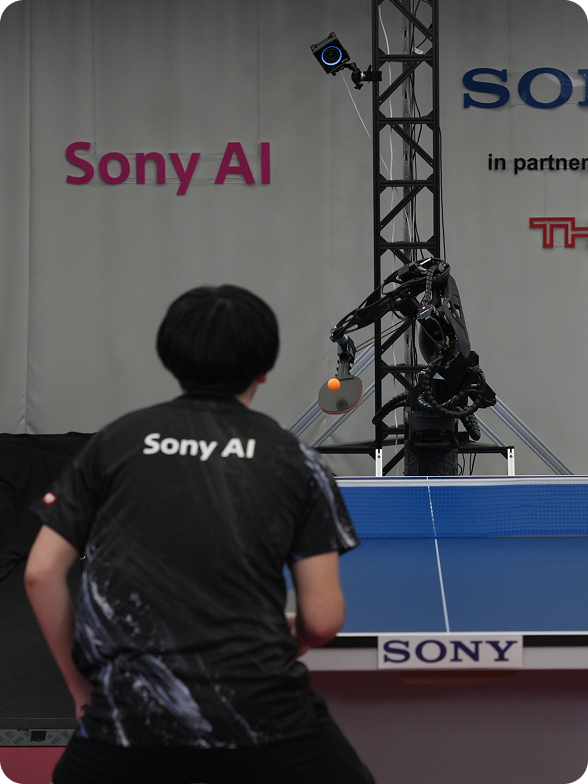 A male athlete plays table tennis with an autonomous robot.